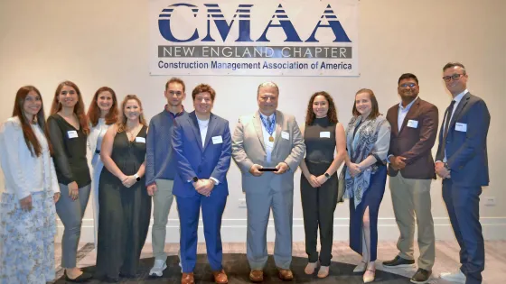A group of people pose around a man holding an award