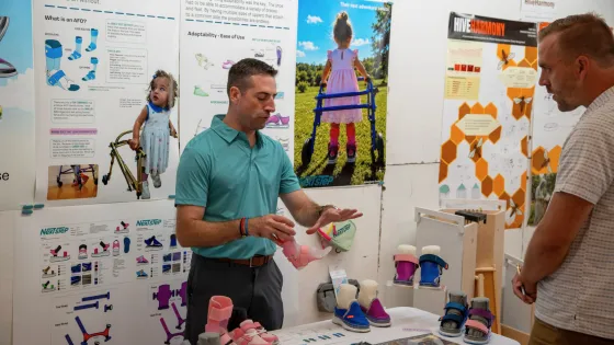 a man explains his shoe prototype to an interested person