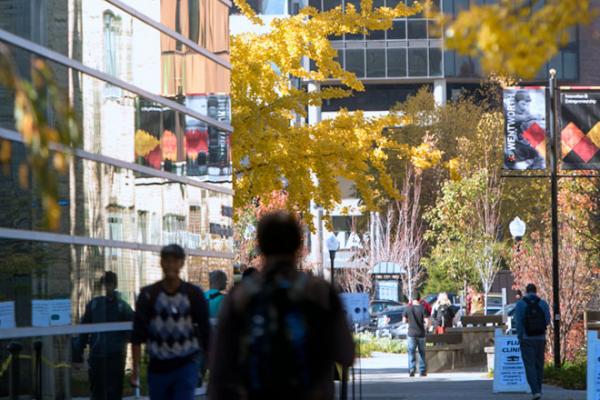 The reflection of the Beatty Hall windows as people walk past.