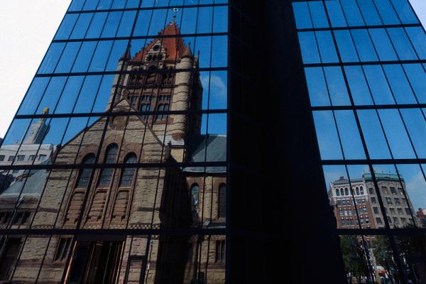 The reflection of Trinity church reflected in a skyscraper.