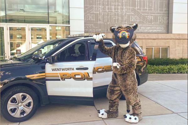 The leopard mascot poses in front of a public safety vehicle.