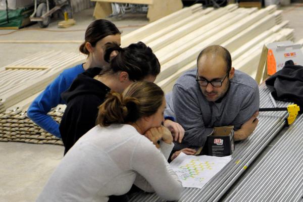 A group of students pour over a blueprint in a construction lab.
