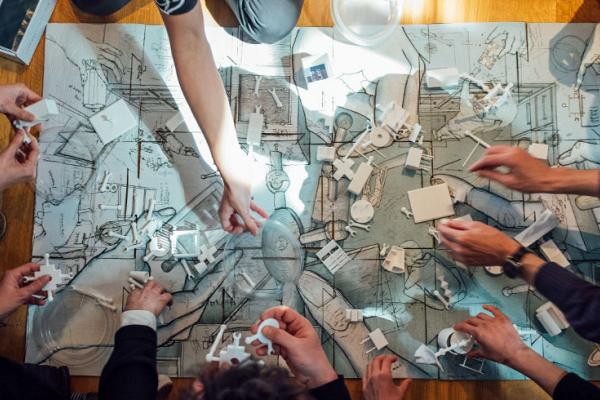 An overhead photo of students hands as they place objects on a map.