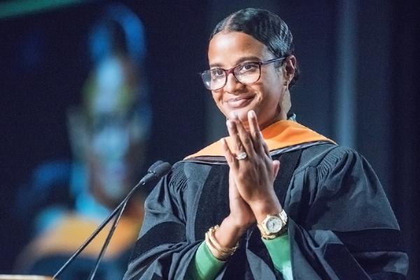 A female student stands at a podium on commencement day.