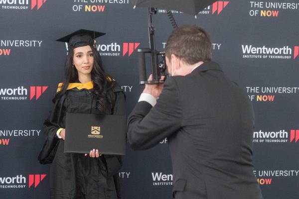 A female Wentworth graduate being professionally photographed with her diploma