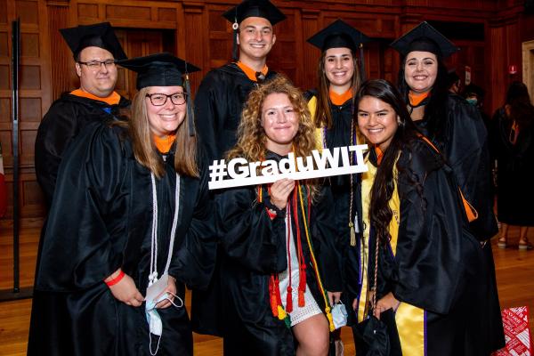 Students in caps and gown posing with "GraduWIT" sign