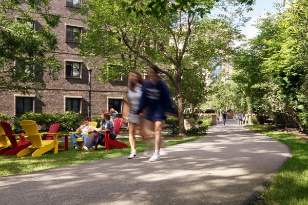 Two women walk through a lively campus