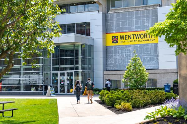 Two students walk towards Beatty Hall in the background with campus greenery in the foreground