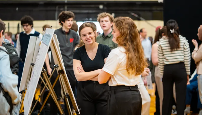 Two women smile in front of their engineering poster at the first year engineering showcase