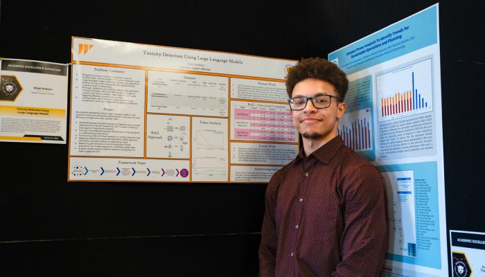 A student stands in front of his poster at the Academic Excellence Showcase
