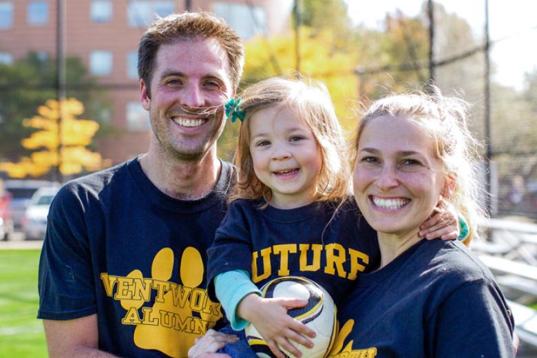 A man, a woman and a child wearing Wentworth alumni t-shirts smile at the camera