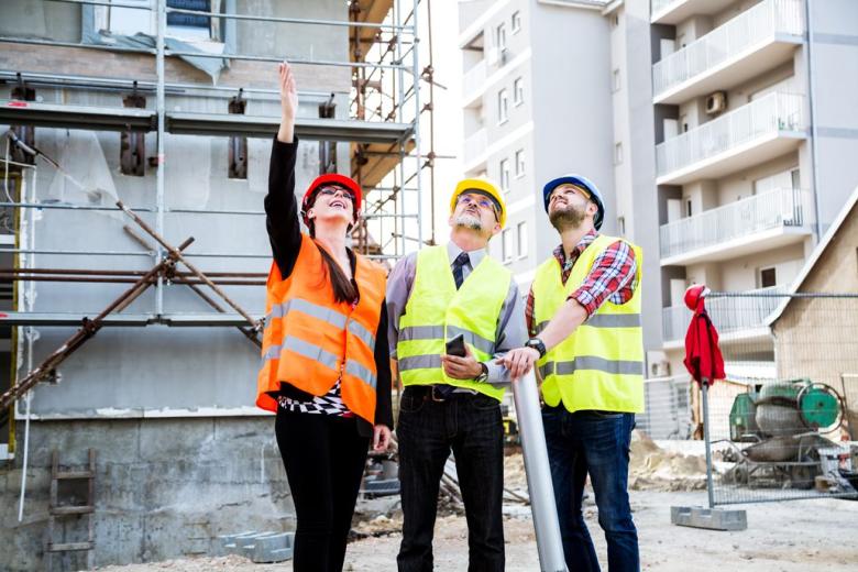 woman and two men on job site looking up