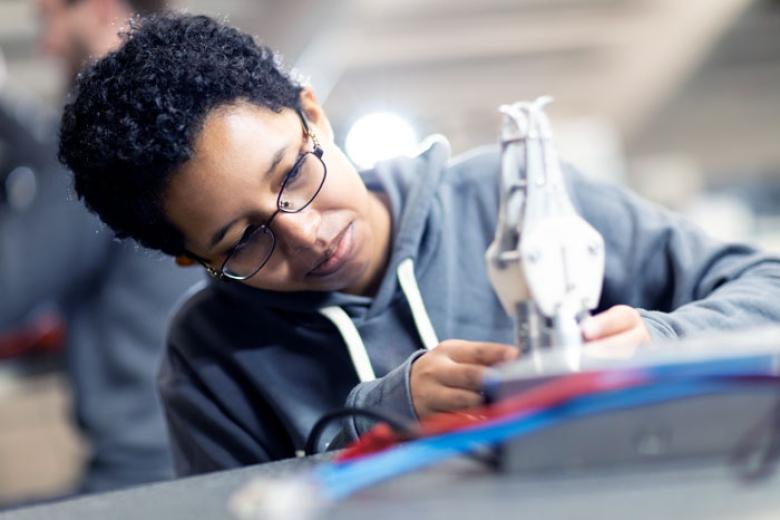 A female student examines a mechanical part. 