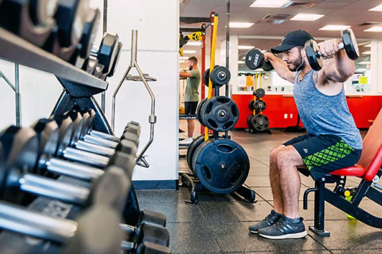 A male student lifts weights in the fitness center. 