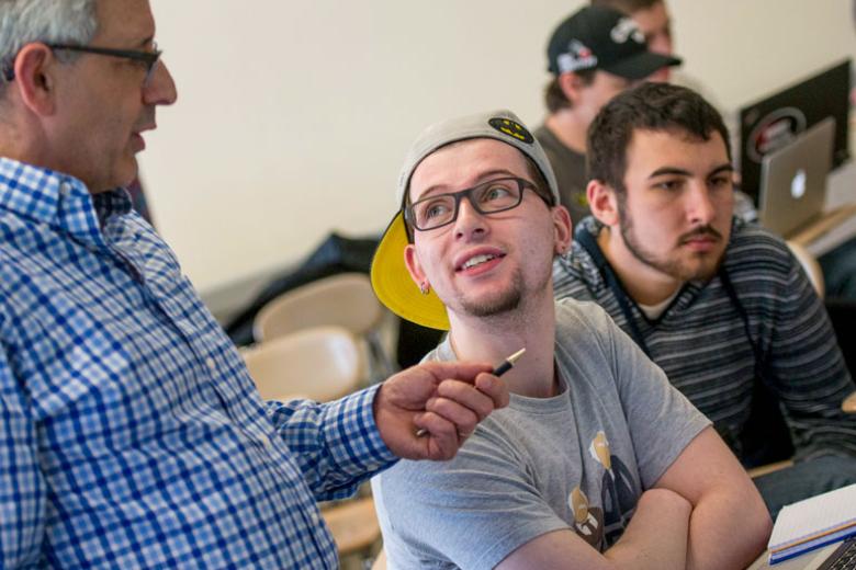 A male student looks up at a faculty member speaking to him.