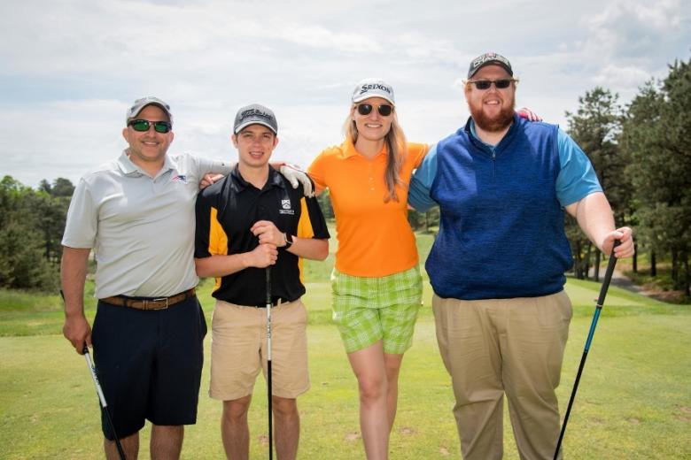 four people posing on a golf course