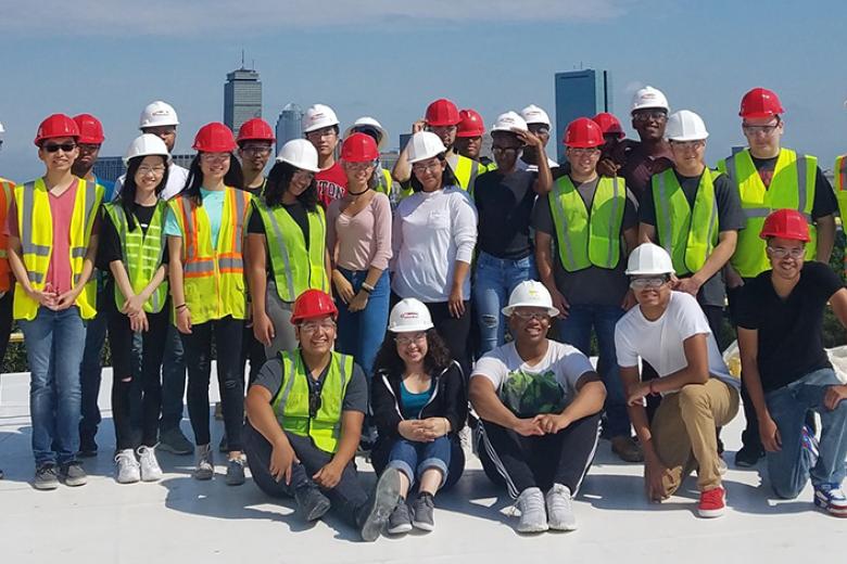 A group of construction management students in front of Boston's skyline.