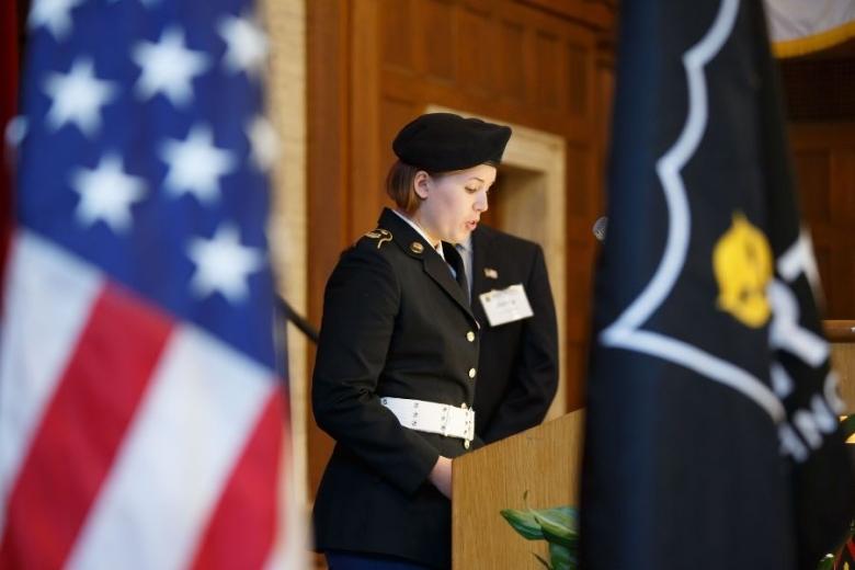 woman in military uniform speaking next to american flag