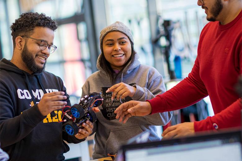 Three students working together on a small robot. 