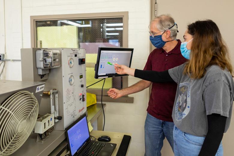 A student and professor examine the display screen of a machine