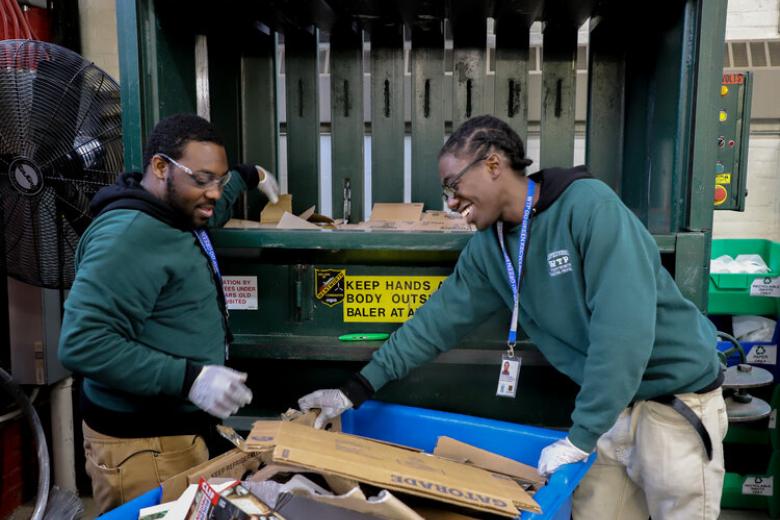 two people cleaning up recycling