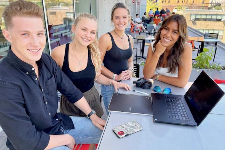 students smile for camera near a laptop