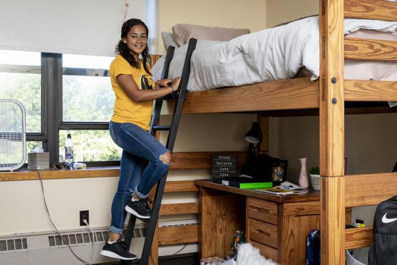 Student near her bed in her dorm