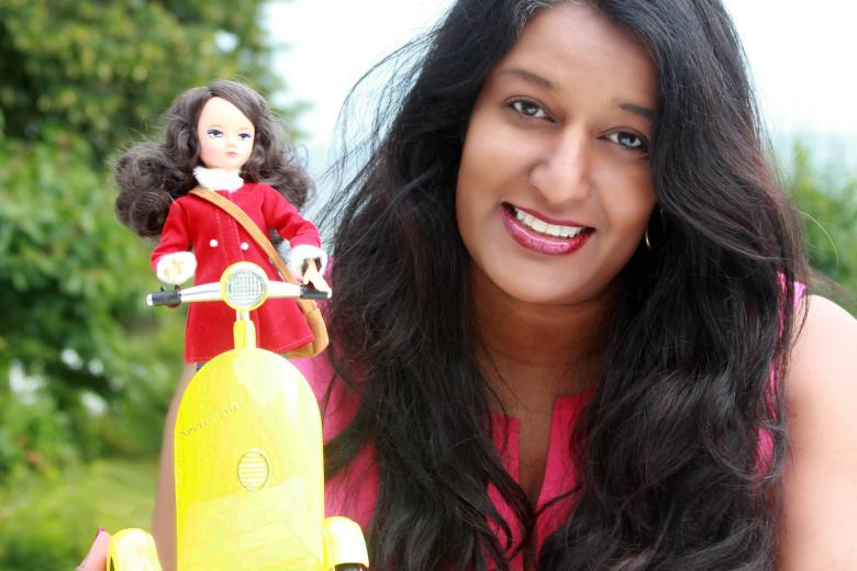 A brown woman with long brown hair in front of her is a doll on a robotics scooter.