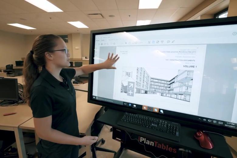 A student demonstrates advanced construction software on a big screen in the classroom