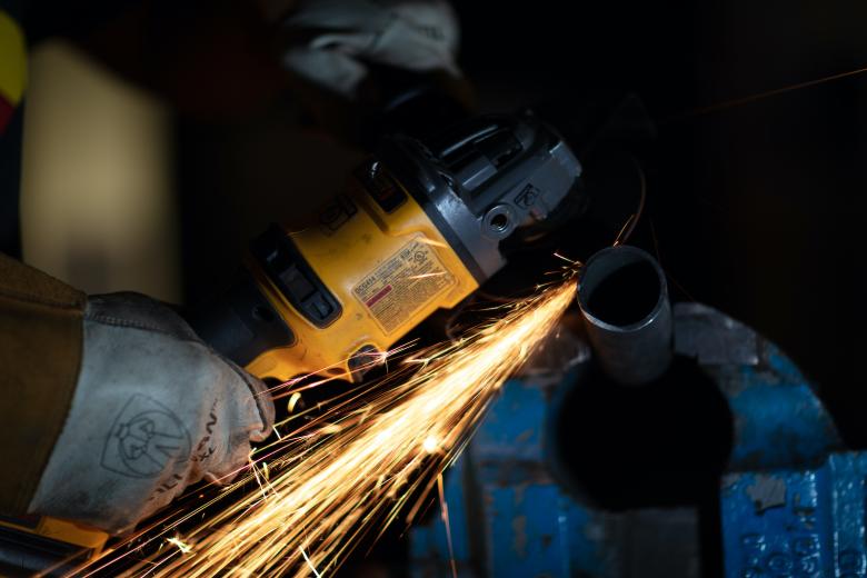 A student uses a grinder to work on a component of a project they're building in the lab