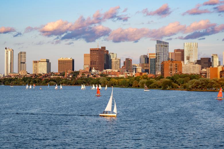 Picture of the Boston skyline in the background as seen from the Charles River with sailboats in the foreground