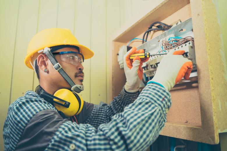 picture of an electrician wearing safety gear while working on breaker panel