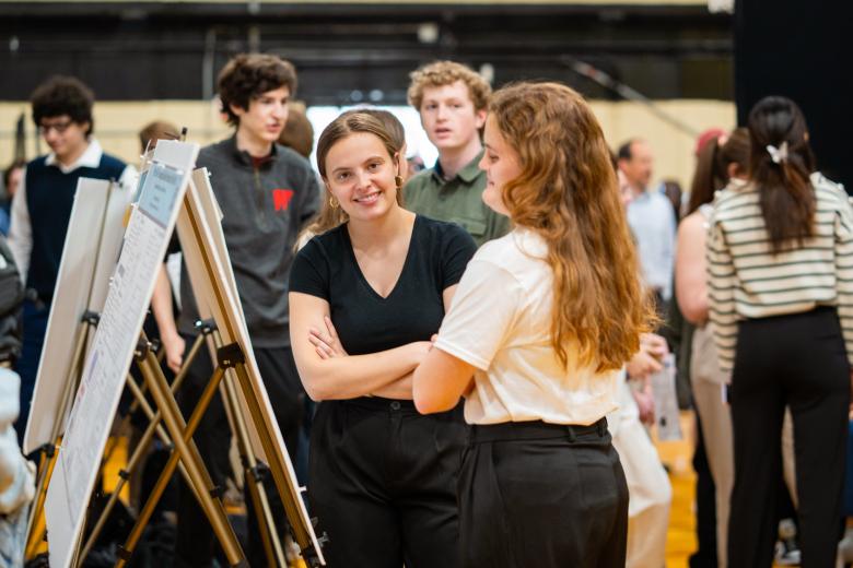 Two women smile in front of their engineering poster at the first year engineering showcase