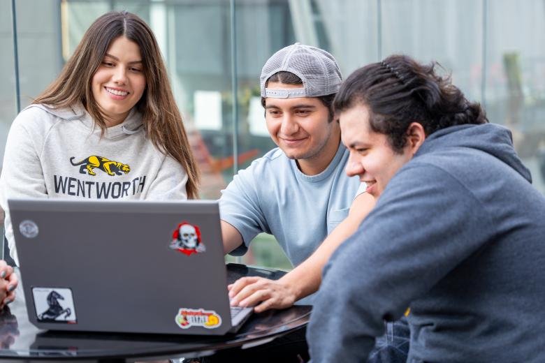Three students looking at a laptop screen