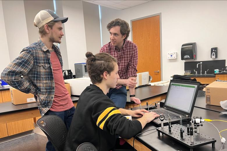 Andrew Seredinski works with two students on a computer in the lab