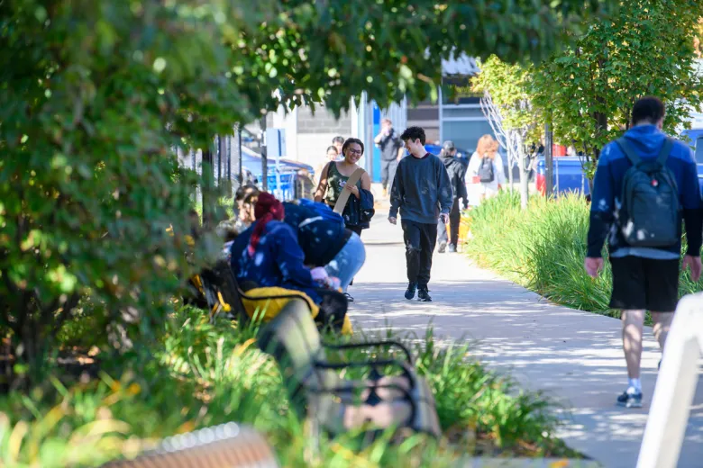 A male and female student walk together toward the quad on a spring day