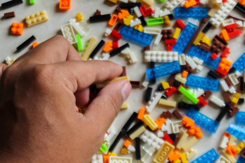 a hand chooses lego blocks from a pile