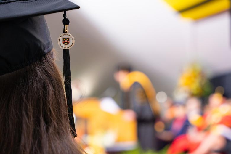 Image of a graduation cap and tassel with a woman with long dark hair