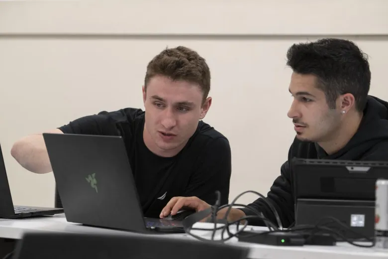 Two students work together on a laptop