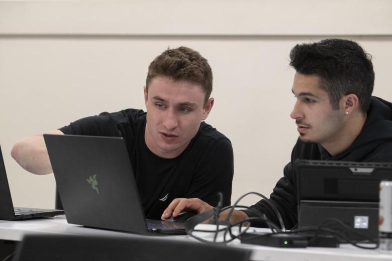 Two students work together on a laptop