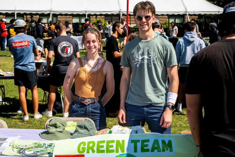 A female and male student stand at a table on the quad for the Green Team during the Student Involvement Fair