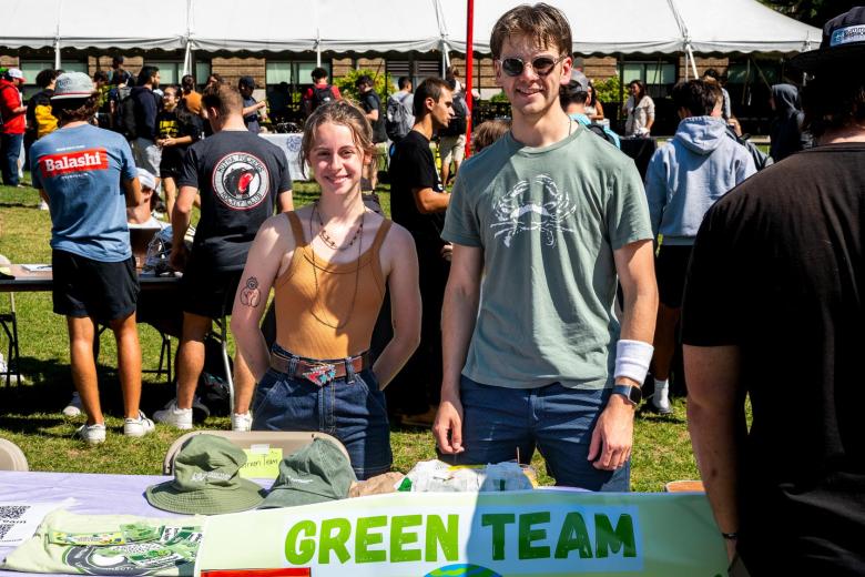 A female and male student stand at a table on the quad for the Green Team during the Student Involvement Fair