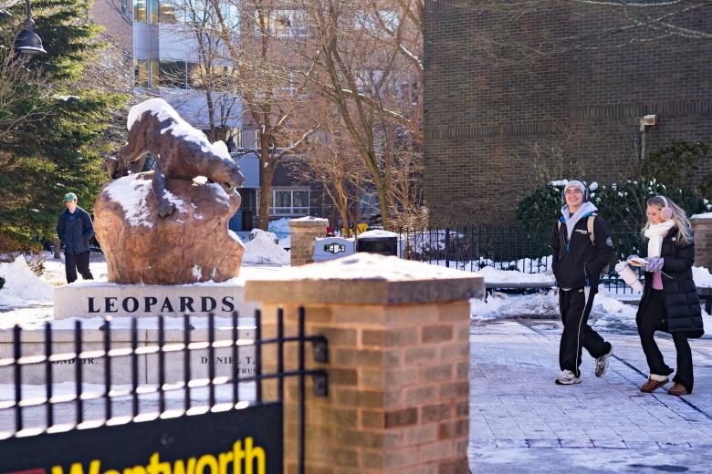 statue of a leopard in the snow with students walking by