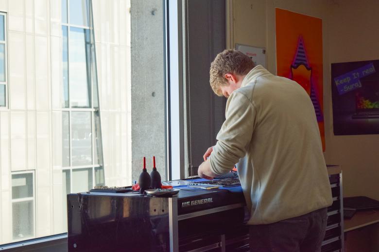 Person with their head down repairing a laptop
