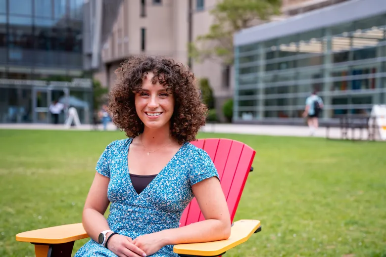 Woman student sitting on quad smiling