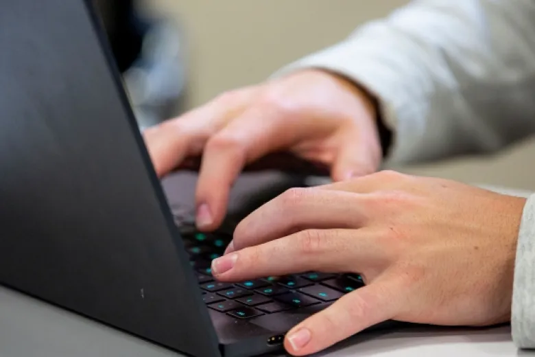 hands typing on a laptop keyboard