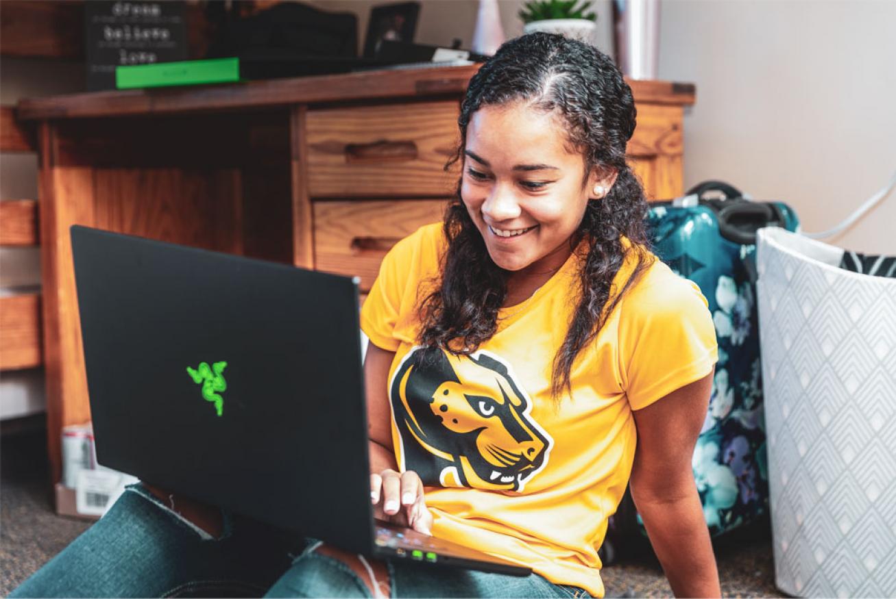 A girl in a Wentworth t-shirt looking at her laptop