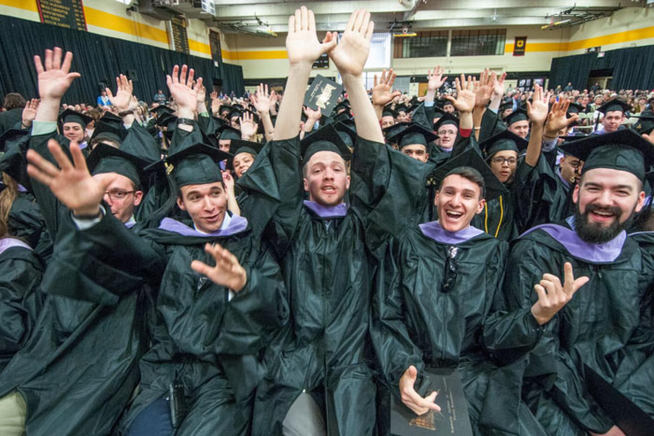 A group of students celebrate in their commencement cap and gown