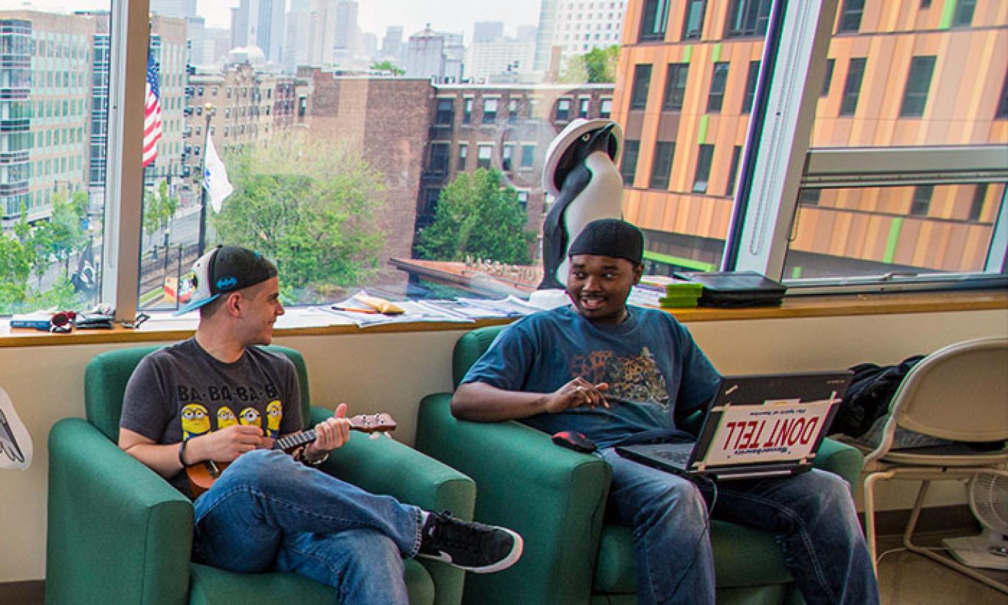 Two males students having a conversation are seated in the dorm common area