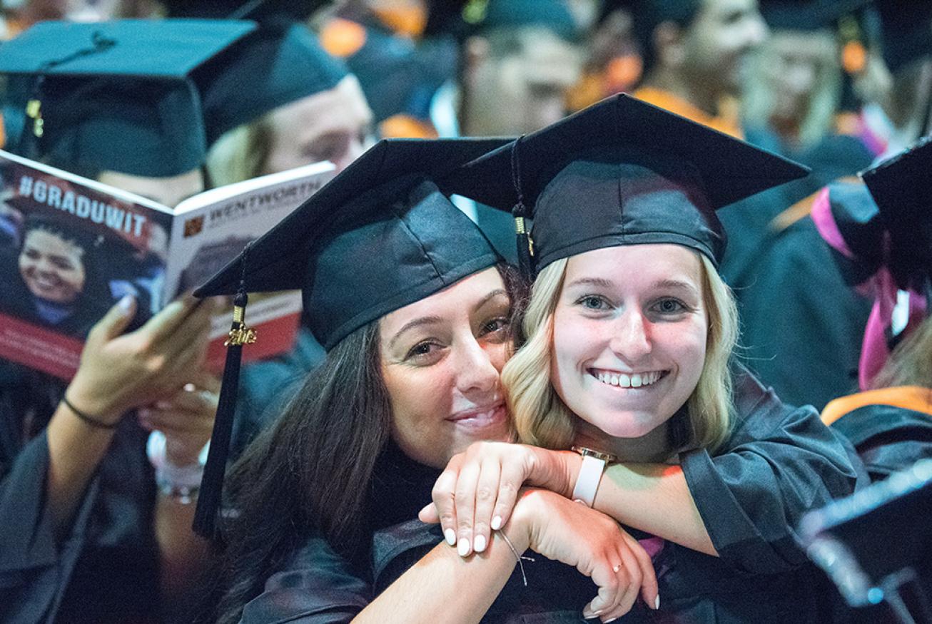 Two women in caps & gowns attending commencement.